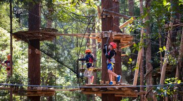 Two children completing an obstacle course in a forrest.