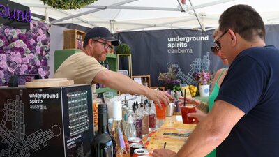 Outdoor stallholder serving drinks to customers.