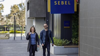 A man and woman walks alongside a hotel exterior.