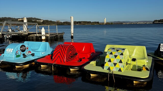 Three small pedal boats docked on a lake.