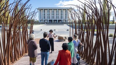 A  tour guide speaking to a group outside the National Library of Australia.