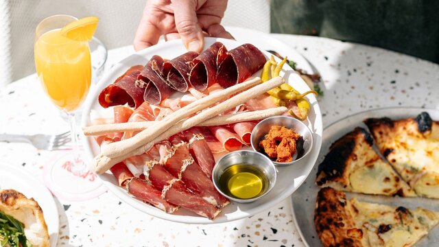 A plate of cold meats served on a platter outdoors.
