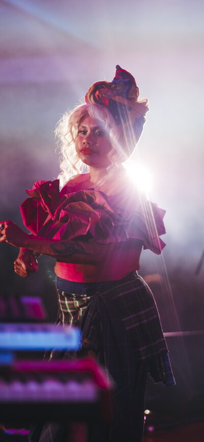 A woman wearing a costume with frilly sleeves, dancing on stage. 