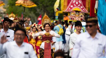 People in traditional Indonesian costumes walking in a street parade.