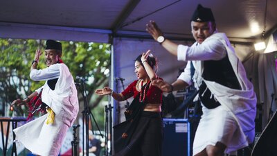 Three people on stage performing a cultural dance.
