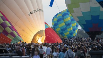 Many colourful hot air balloons inflating.