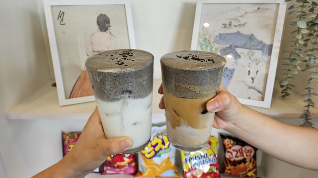 Two unique iced drinks in front of a shelf of snacks