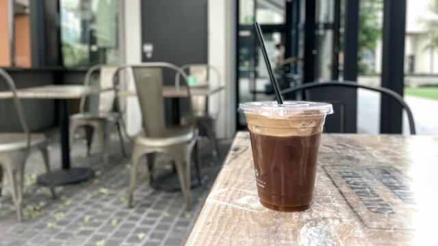 An iced drink in a plastic cup on an outdoor table.