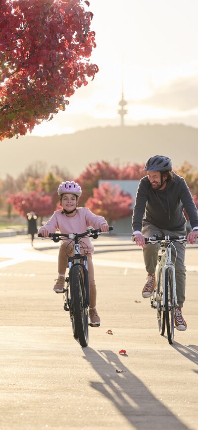 Father and daughter on bikes with autumn leaves in the background