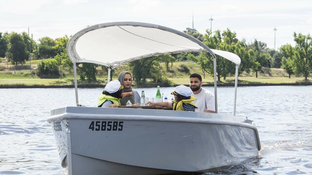 A family on an electric boat having a picnic