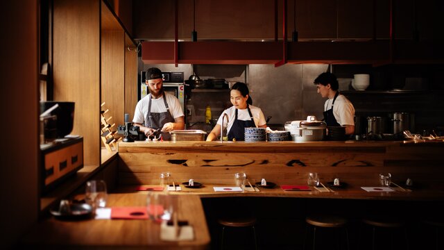 A dim-lit Japanese eatery with chefs in the open kitchen