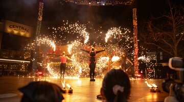 Performers on an outdoor stage with bright fire displays