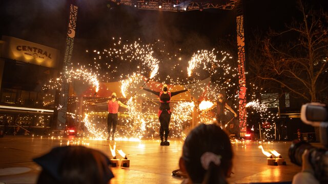Performers on an outdoor stage with bright fire displays