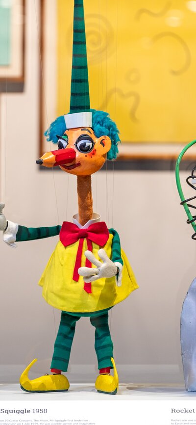 Three colourful puppets next to each other in a display cabinet