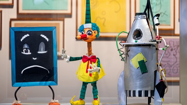 Three colourful puppets next to each other in a display cabinet