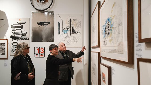 Three people in a gallery pointing at the work