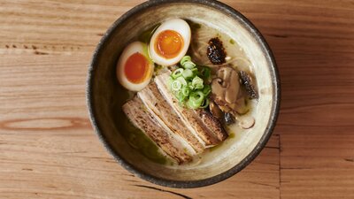 A bowl of traditional ramen with noodles. eggs, meat and vegetable