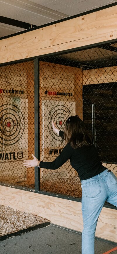 Two participants trying to throw a wooden axe