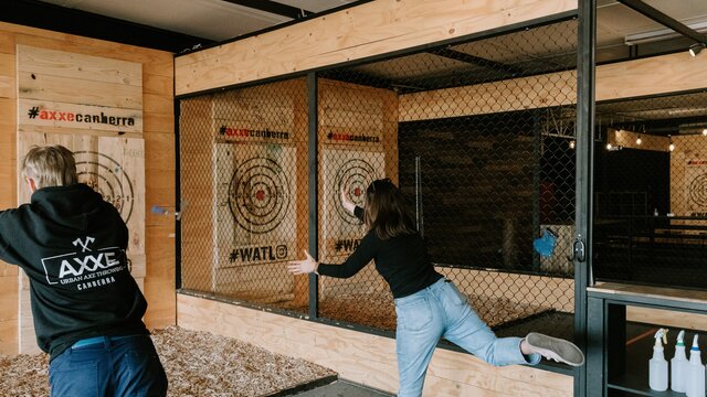 Two participants trying to throw a wooden axe