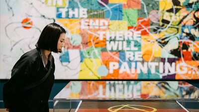 A visitor at an art gallery observing an artwork on a table