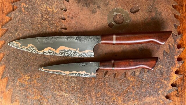 Two knives in front of a rust background