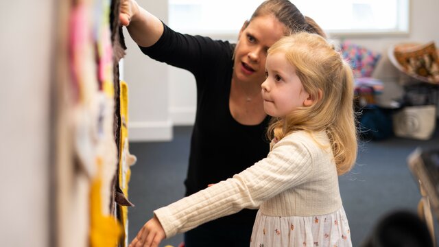 A mother and child place felt faces on a wall