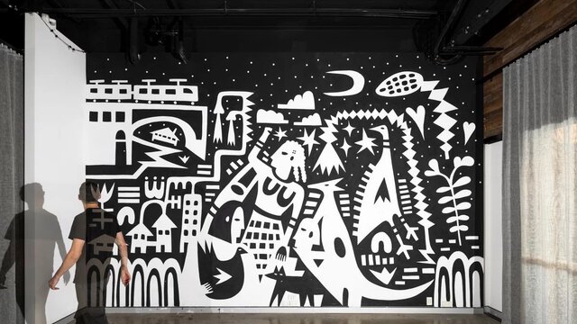 A person walking past a black and white artwork on a wall