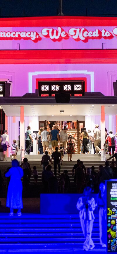 A crowd of people outside a large illuminated building