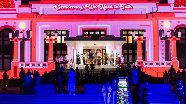 A crowd of people outside a large illuminated building