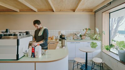 A man making a coffee in a neutral cafe setting