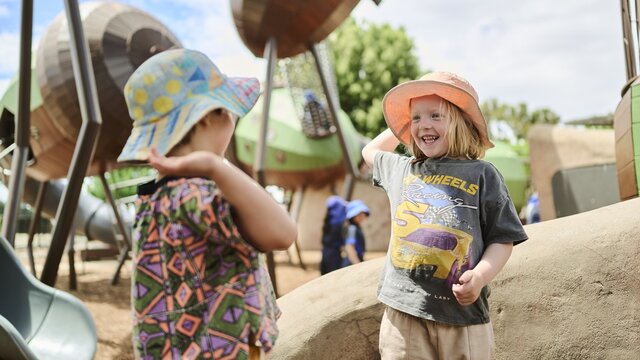 Two small children doing a "high five" at a playground