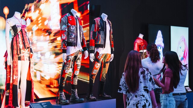 Two people looking at vibrant costumes on display