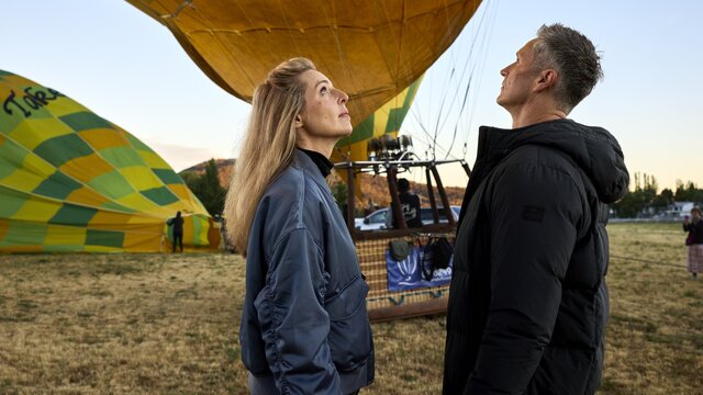 A couple looking up at a colourful hot air balloon inflating