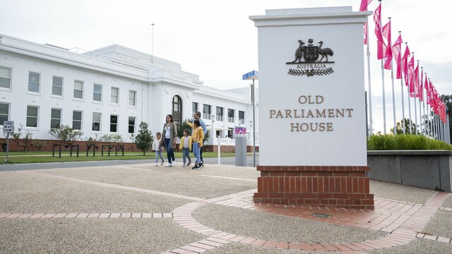 A young family walk outside the entrance of a museum