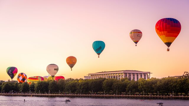 Several colourful hot air balloons drifting above the water