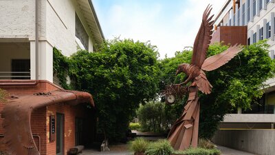 Two rust colour sculptures with greenery in the background