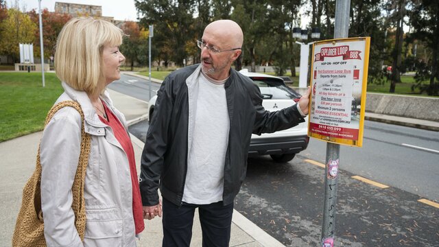 A couple stands at a bus stop