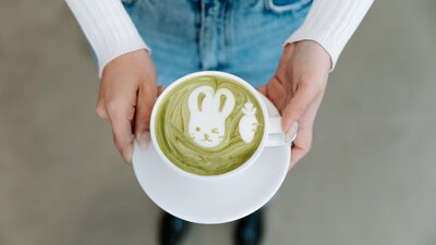 Hands holding matcha coffee with design of bunny on top