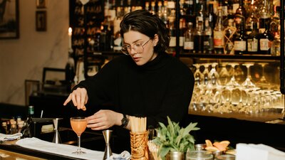 Person making a cocktail at a bar countertop