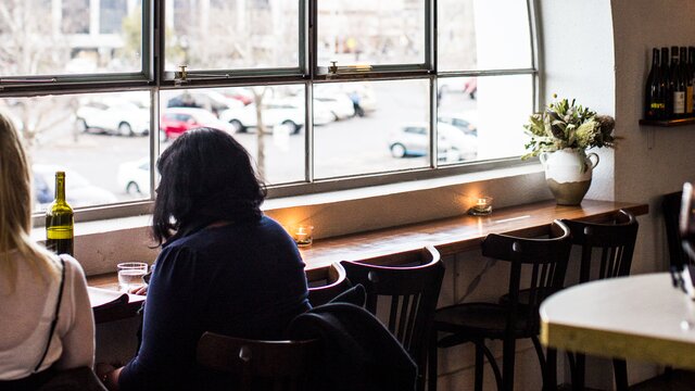 Two people sitting at a table in front of a large window