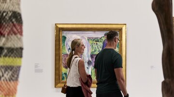Two people walking past a vibrant bright painting