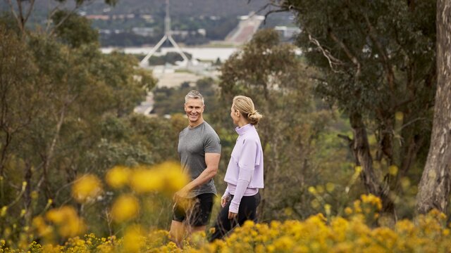 Two people look at each other while on a walk with national attractions behind them
