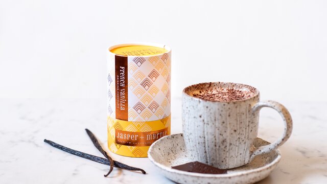 One hot chocolate in a mug and a yellow cylinder of hot chocolate powder