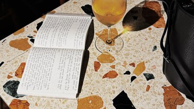 Jenna Rowe with notebook and wine at Monster Bar, Ovolo Nishi A notebook sits open next to a glass of wine on a colourful countertop at Monster Bar at Ovolo Nishi