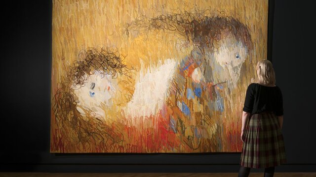 The back of a person looking at a large colourful artwork in a gallery