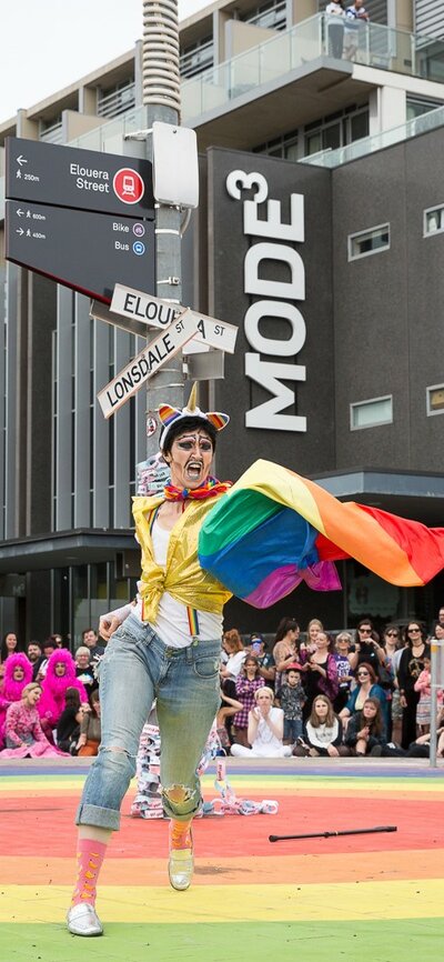 Pride performer dancing on top of the rainbow circle roundabout in Braddon, ACT with crowds watching. | © Cassie Plum Photography