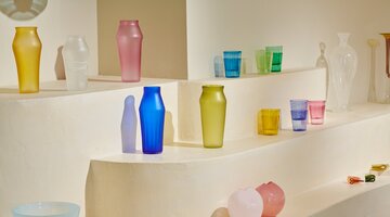 Colourful glass art, vases and glasses on shelves.