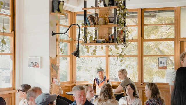 A light filled cafe with big windows and wooden features.