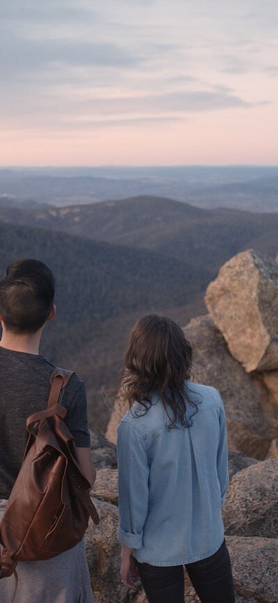 A couple standing at the rocky peak of Booroomba Rocks.