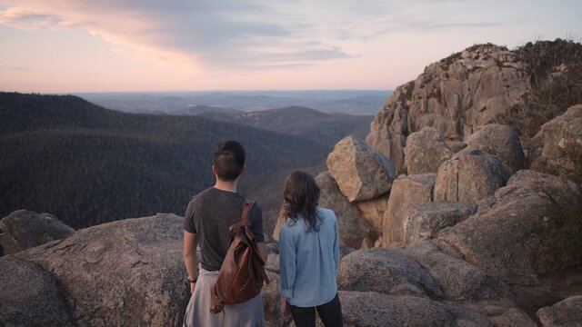 A couple standing at the rocky peak of Booroomba Rocks.